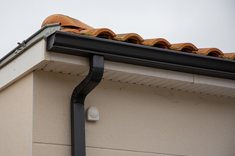 metal black gutter home roof covered with ceramic tiles close up